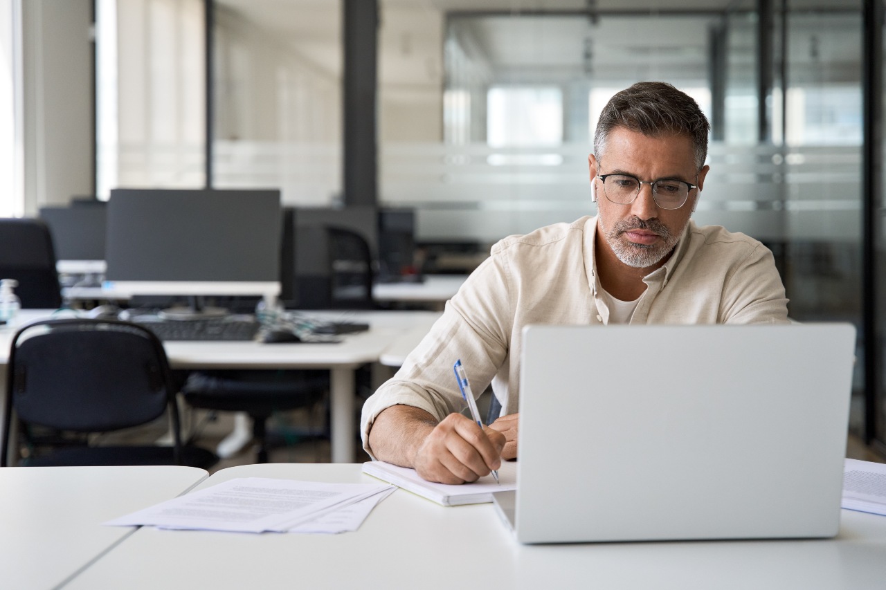 Man writing notes during virtual meeting